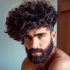 Bearded man with tousled dark hair and piercing eyes