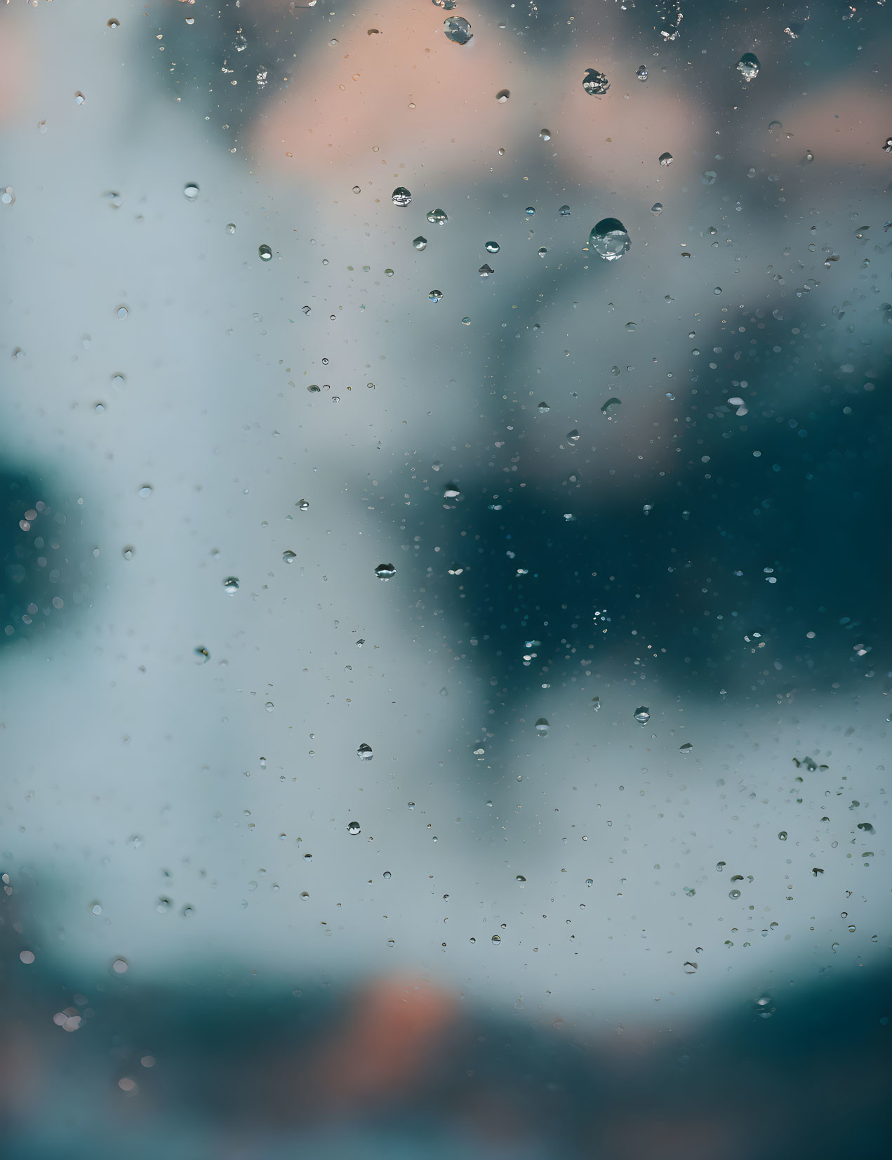 Raindrops on glass with urban background captured in close-up.