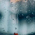 Raindrops on glass with urban background captured in close-up.