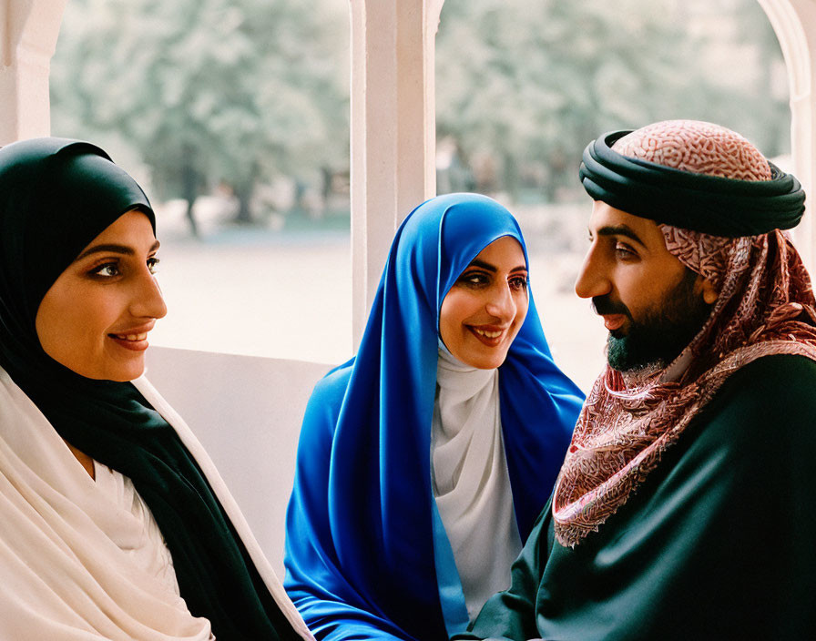 Traditional Middle Eastern attire: Two women in hijabs and a man in a keffiyeh convers