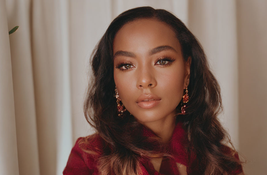 Portrait of woman with bold eyeliner, red outfit, and earrings