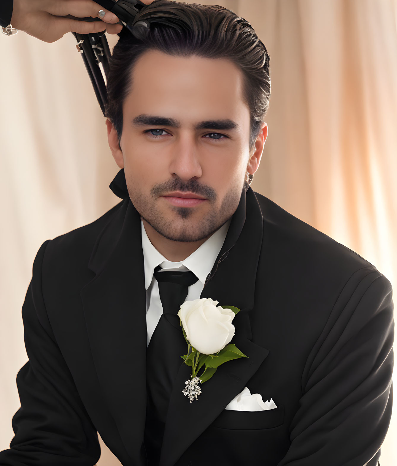 Formal man in black tuxedo with white rose boutonniere and bow tie.