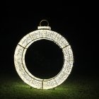 Person standing under giant ring of lights with Saturn-like top against dark starry sky