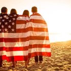 Group of four people in desert with US flag at sunset