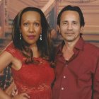 Formal couple posing with vibrant bouquet against terracotta backdrop