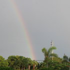 Person in Cape and Helmet Admiring Double Rainbow in Field