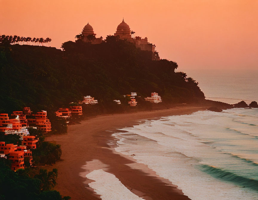 Sandy beach, foamy waves, greenery, and buildings under hilly area at sunset