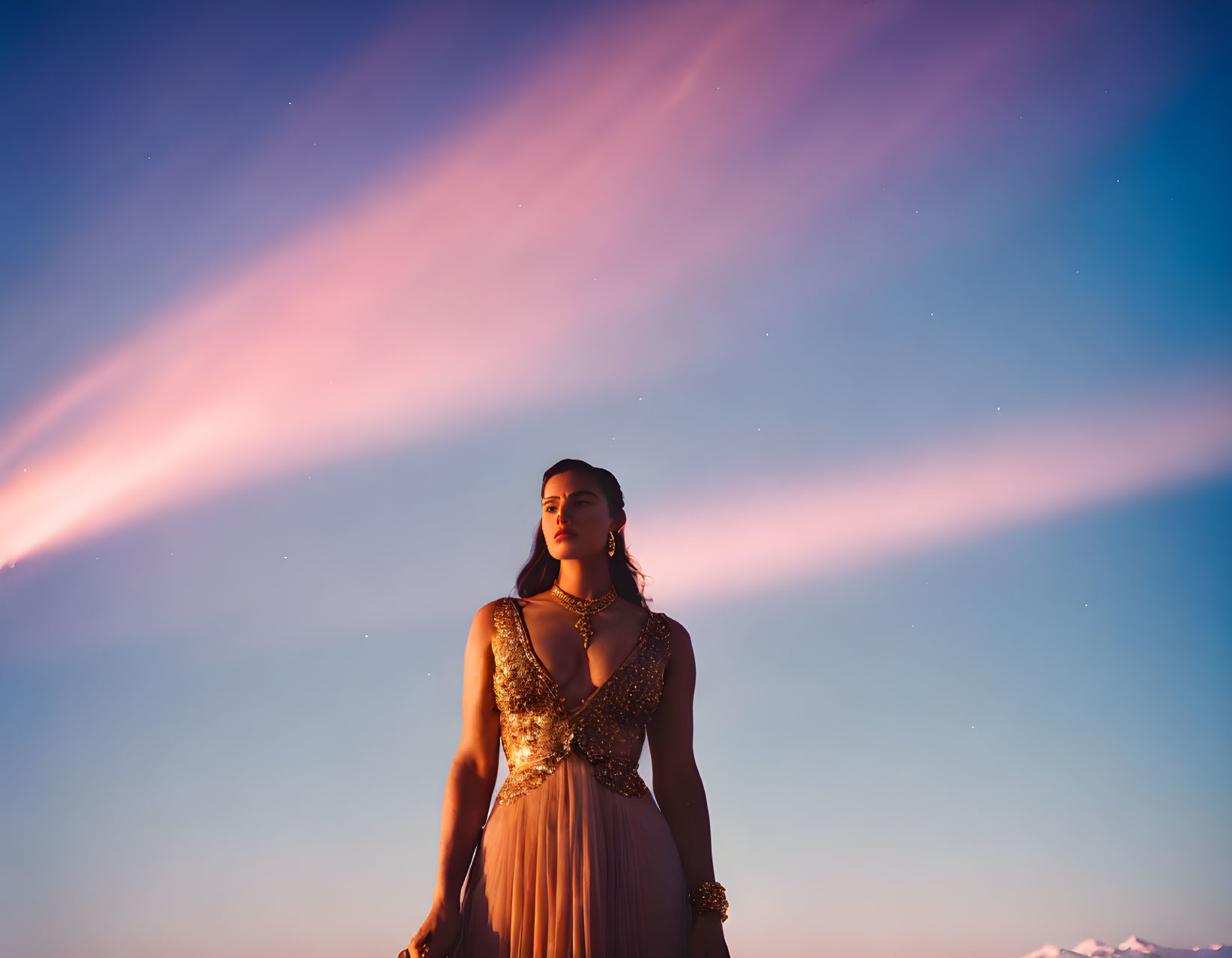 Elegant woman in dress under twilight sky with streaked clouds