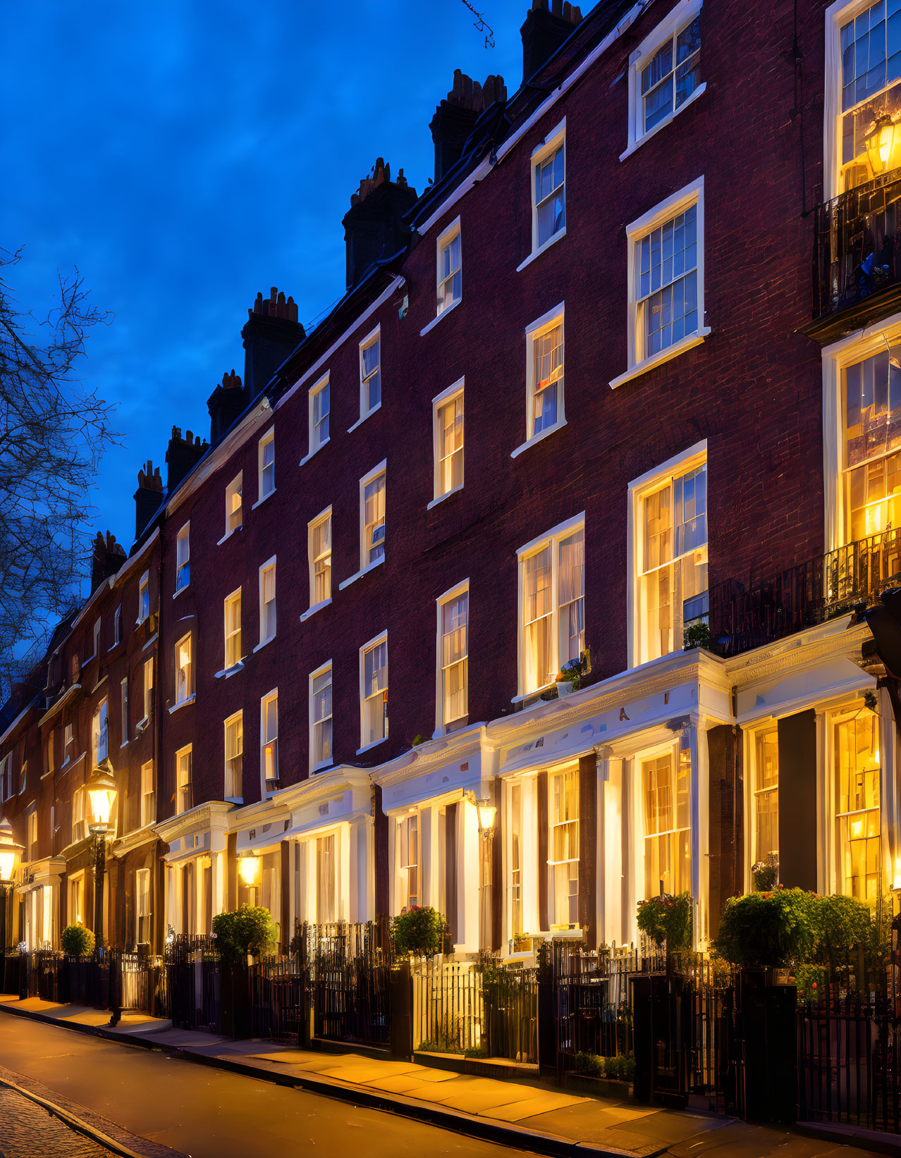 Brick townhouses glowing under street lamps at dusk