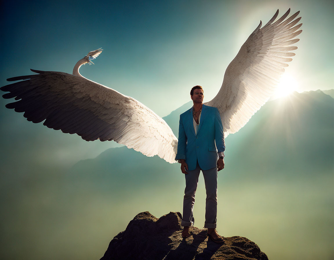 Man with angelic wings on rocky outcrop in misty background