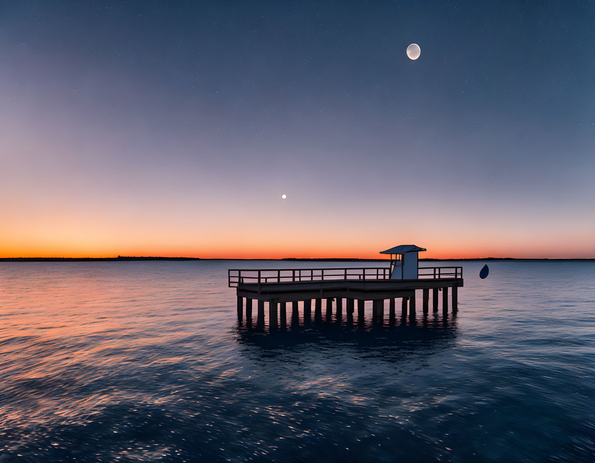 Tranquil lake scene with pier, lifeguard stand, Venus, and crescent moon