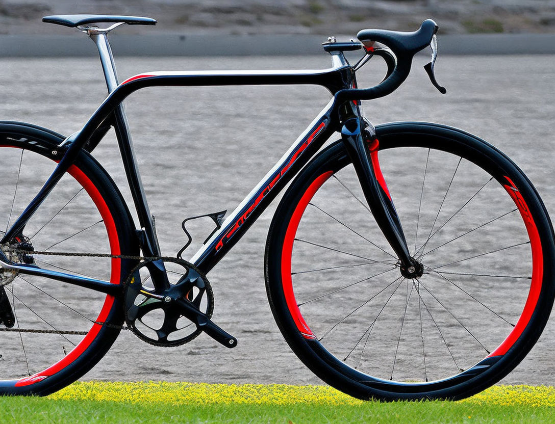 Black Frame Road Bicycle with Red Accents on Gray Surface with Grass