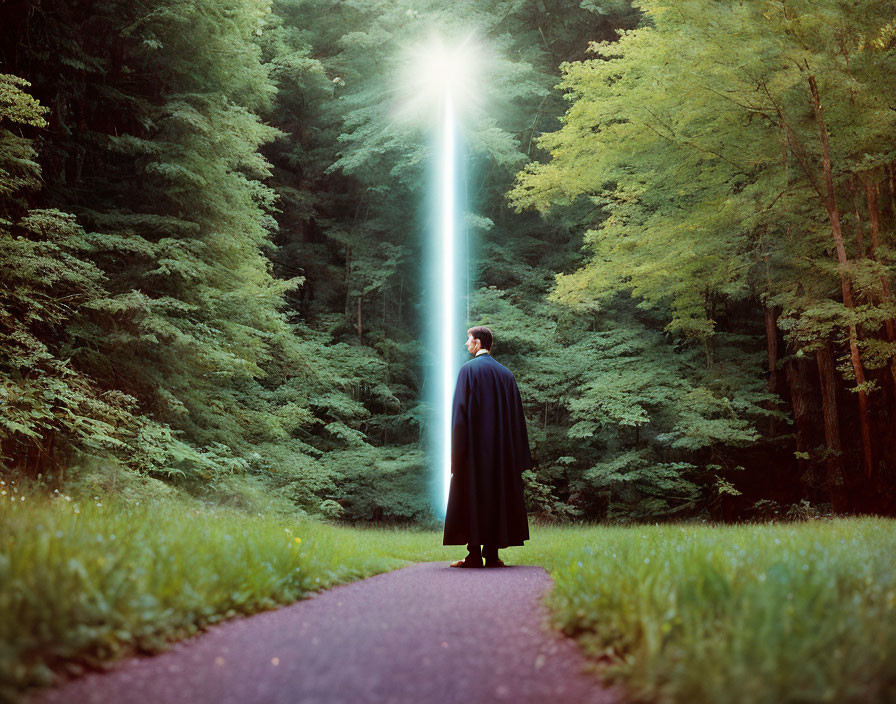 Figure in cloak on forest path under beam of light