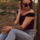 Woman in torn jeans and off-shoulder top on boat at sunset