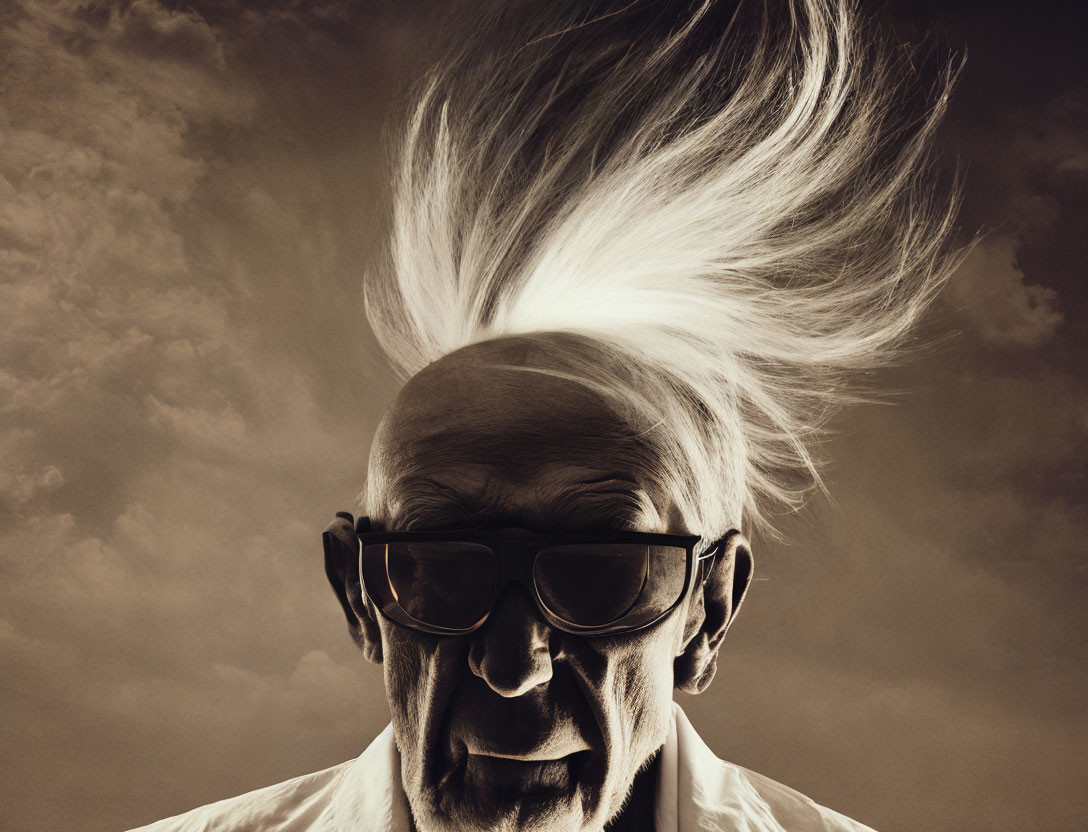 Elderly man with windswept white hair and sunglasses in stormy background