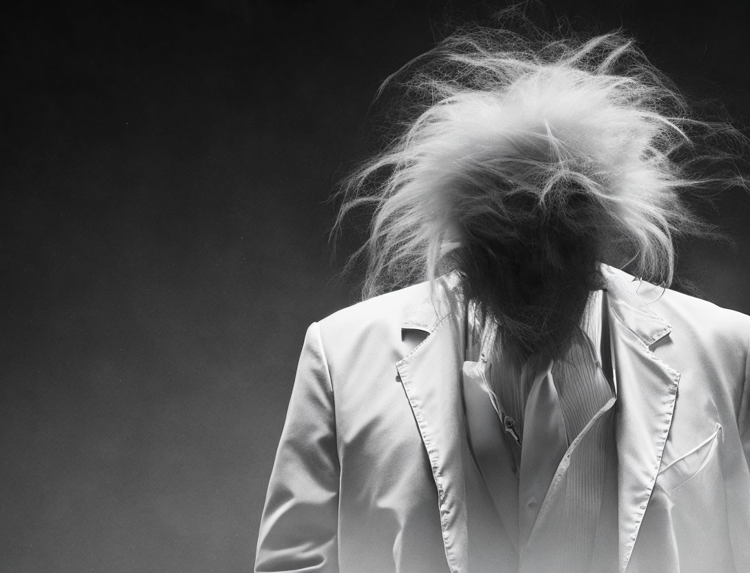 Person in White Blazer with Head Tilted Down on Dark Background