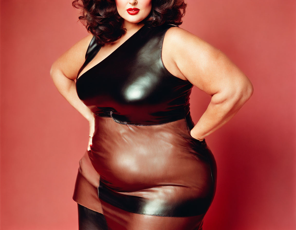 Confident woman in glossy black halter dress against red backdrop