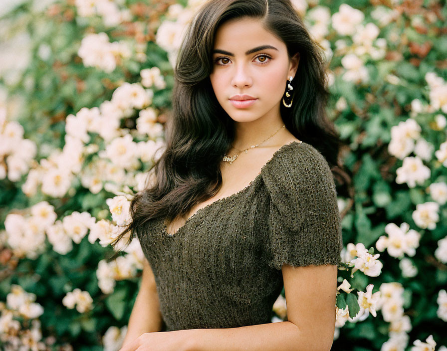 Dark-Haired Woman with Earrings Posing by White Flower Bush