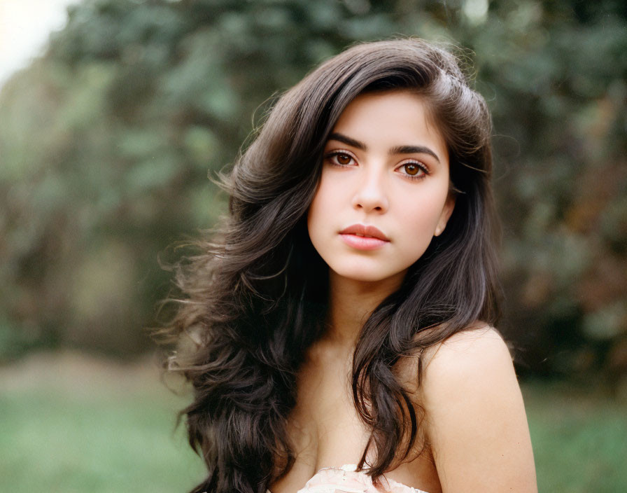 Portrait of woman with long dark hair and brown eyes on green background