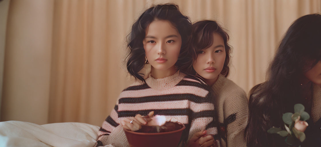 Two Individuals Posing with Plant Pot in Front of Warm-Toned Curtain