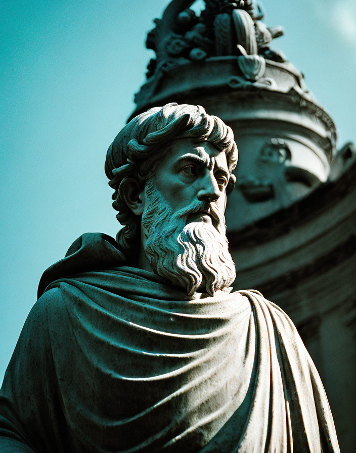 Bearded male bronze statue in classical drapery against blue sky