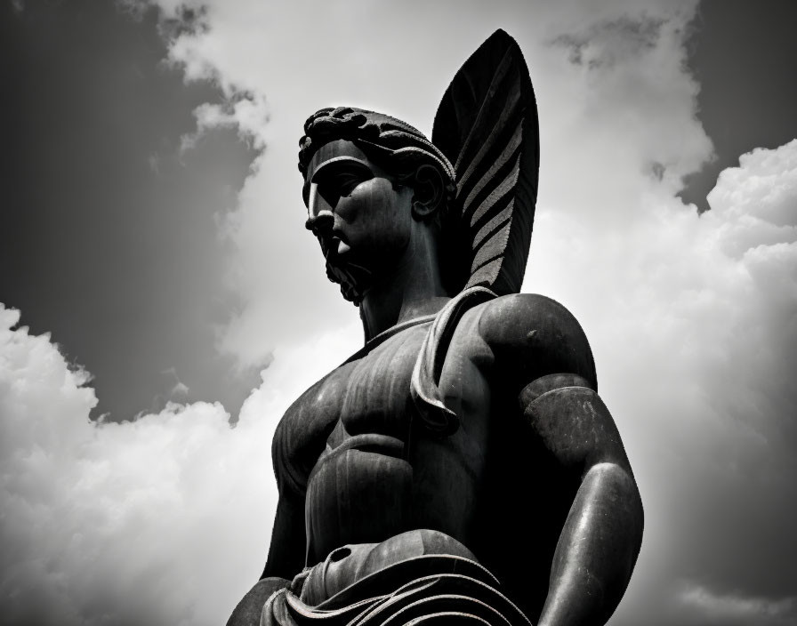 Winged male statue silhouette against dramatic clouds