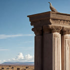 Ornate classical columns with bird against blue sky