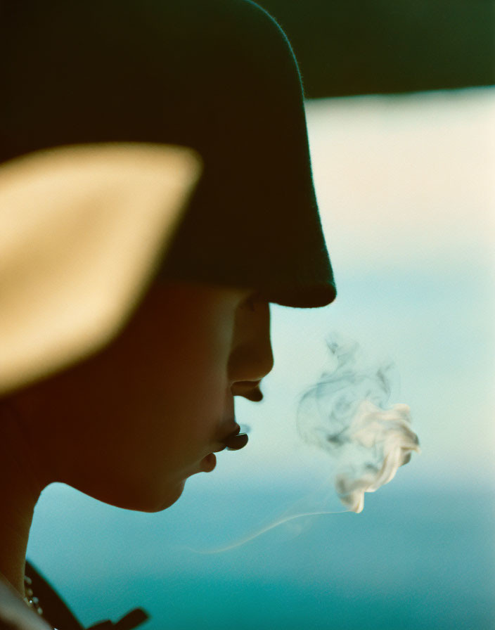 Person in Hat with Smoking Mouth Against Blurred Background