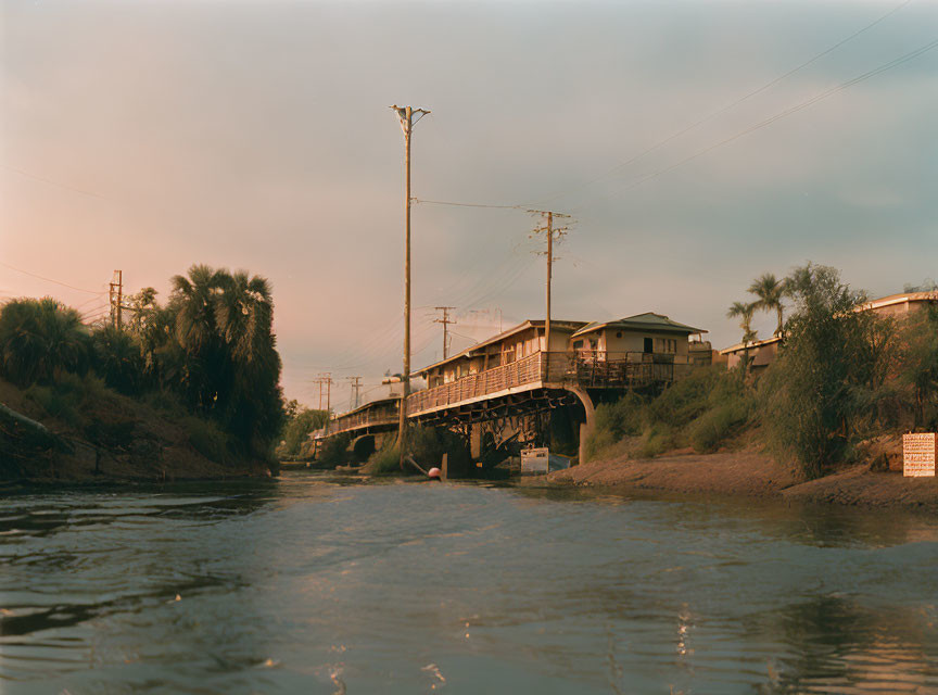 Tranquil riverscape at dusk with train on bridge