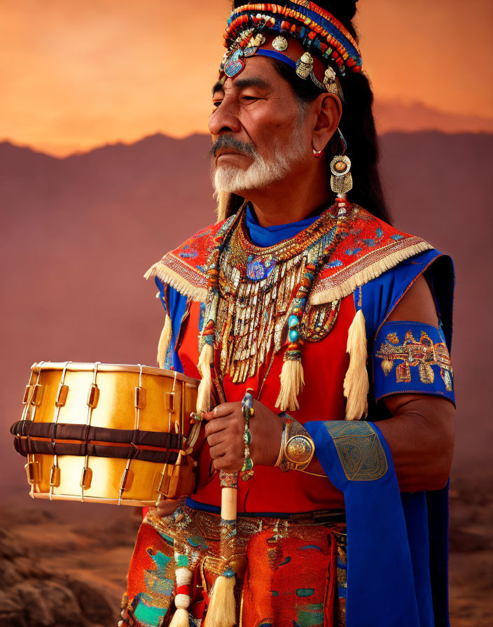 Native American man in traditional regalia with drum at sunset.