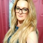 Blonde woman with gold tiara and butterfly hair accessory on pink backdrop