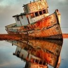 Abandoned ships with peeling paint in calm water under hazy sky