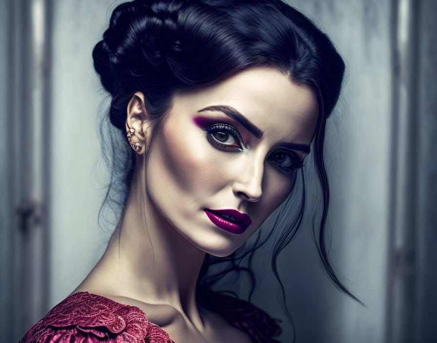 Dark-haired woman in bold makeup and red lace dress against grey backdrop