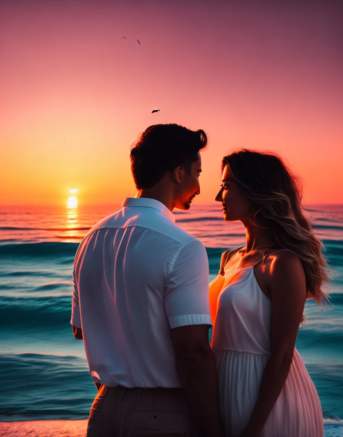 Couple gazing at each other against vibrant sunset by ocean