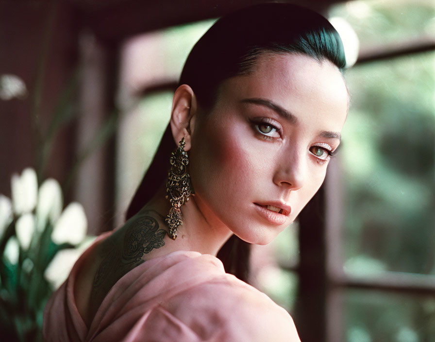 Sleek Hairstyle Woman with Earrings and Shoulder Tattoo Poses by Window