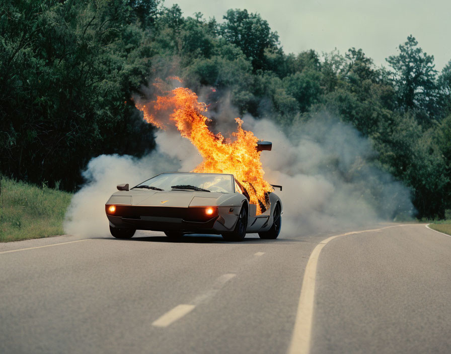 Flaming sports car on road with smoke and trees