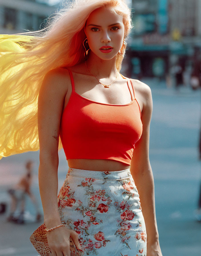 Blonde woman in red crop top and floral skirt on sunny street