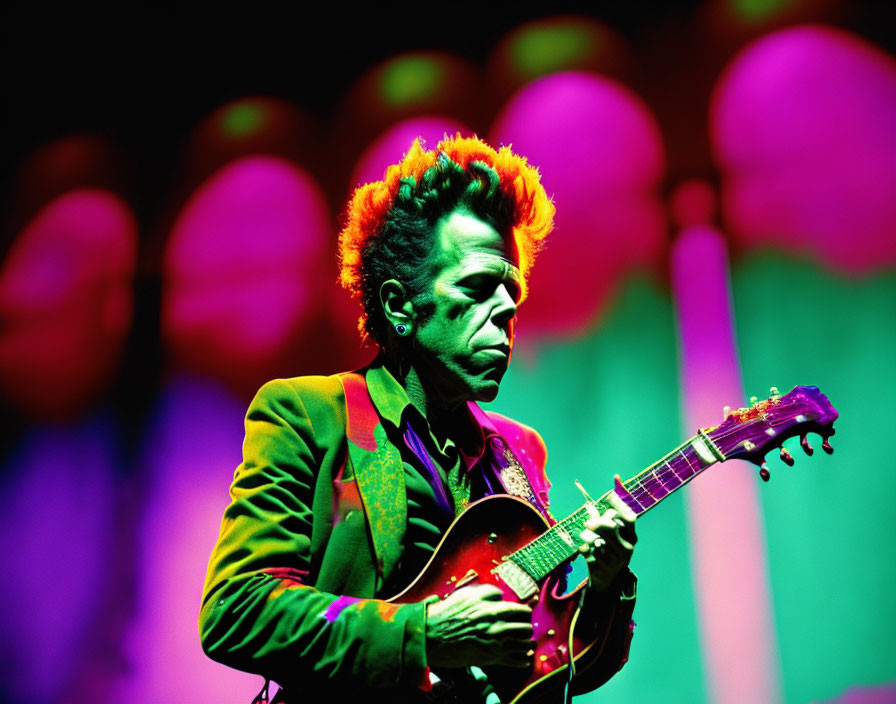 Musician with Orange Hair Plays Guitar on Stage Amid Green and Pink Lights