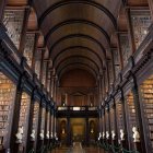 Sunlit library with towering bookshelves and central table stacked with books