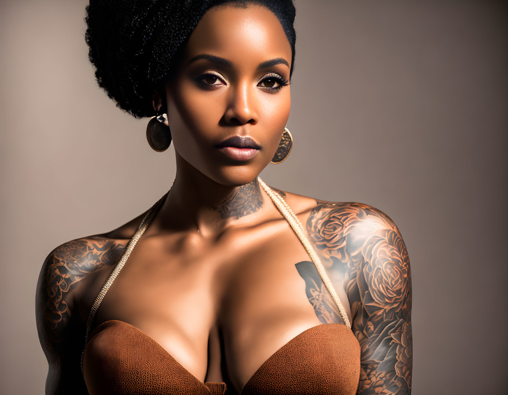 Woman with elegant afro hairstyle, tattoos, hoop earrings, brown top on beige backdrop.