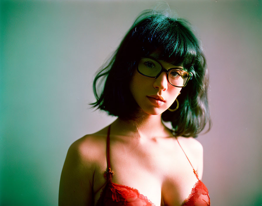 Black-Haired Woman in Glasses with Red Top on Softly Lit Background