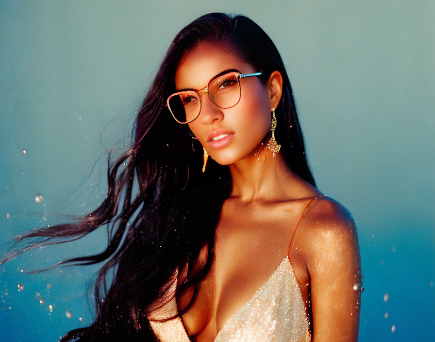 Dark-haired woman in glasses wearing off-shoulder attire on blue background with specks of light