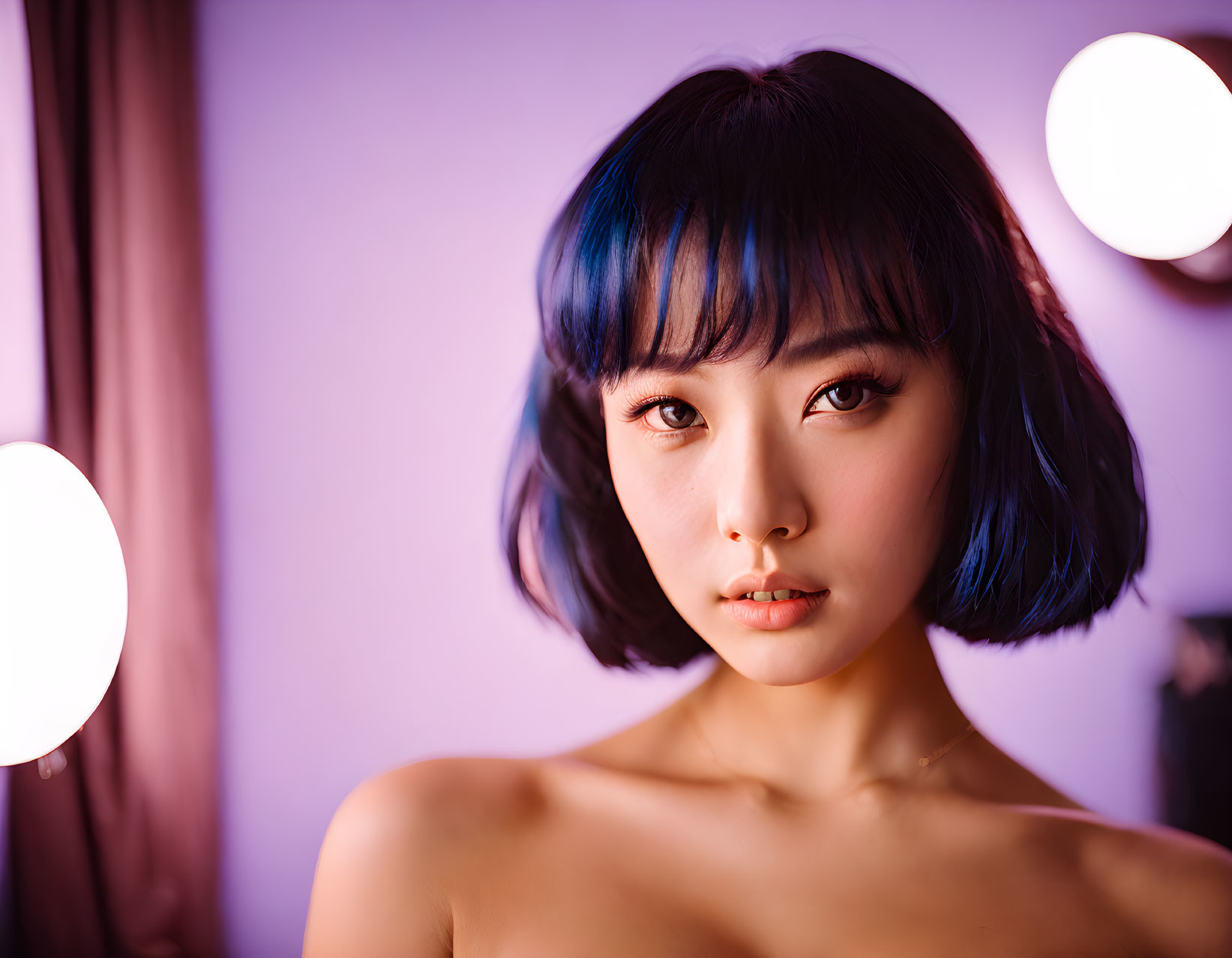 Blue-tinted bob haircut on young woman under soft pink lighting