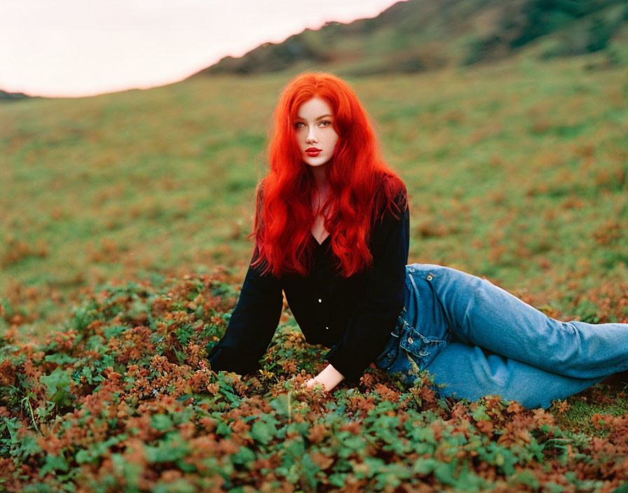 Woman with Red Hair Lying on Green Foliage in Jeans and Black Top