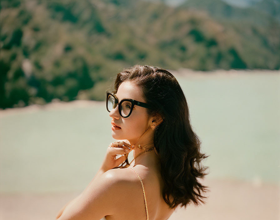 Woman with Black Glasses Looking Over Shoulder in Nature Scene