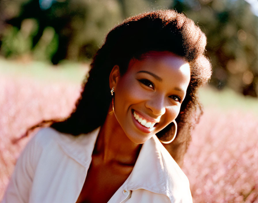 Joyful woman in white shirt surrounded by pink blooms