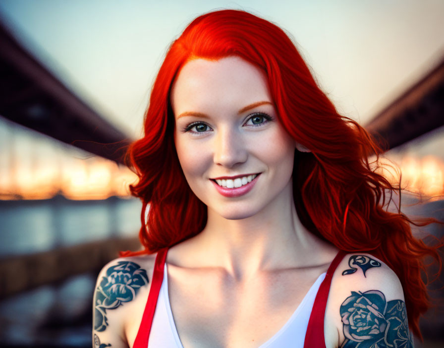 Vibrant red-haired woman with tattoos smiling against bridge architecture background