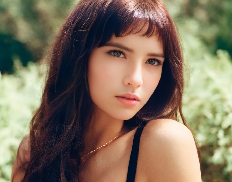 Dark-haired Woman with Bangs in Sunlit Outdoor Setting