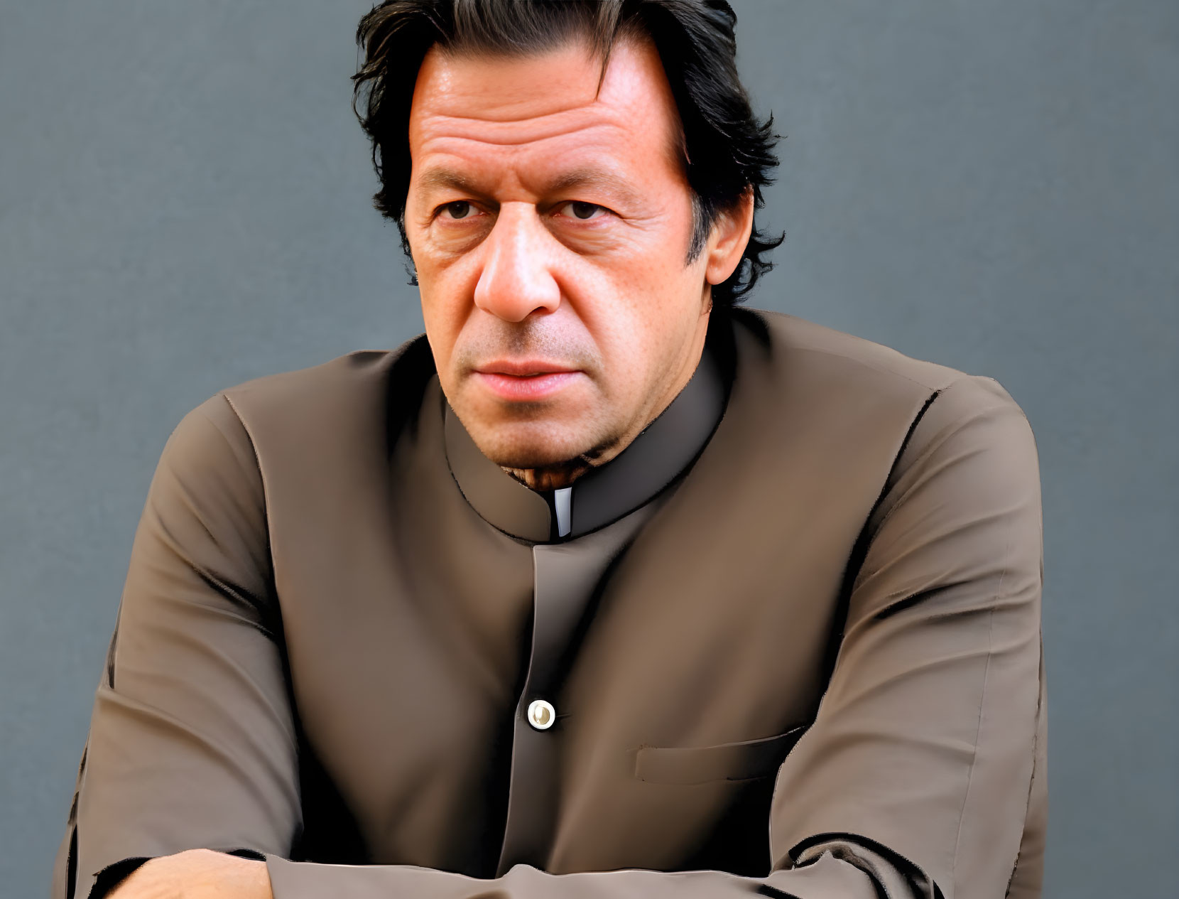 Traditional man in dark brown shalwar kameez against grey backdrop