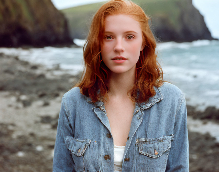 Red-Haired Woman in Denim Jacket on Beach with Cliffs